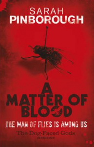 Cover art for A Matter of Blood: title in dark block letters with a fly-like insect silhouetted against the final O in blood. Red background, with a photo of a fly impaled on a pin above the title. White block text subtitle reads 'The Man of Flies is among us'.