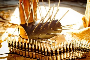 Photo of studded bracelets and bullet belt on a wooden surface glinting in the sunlight. Photo by Robert Bejil, shared under Creative Commons licence