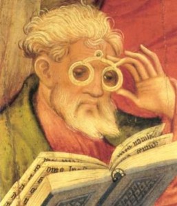 A medieval illumination showing an elderly man reading a book by the aid of large white spectacles. Used under Fair Use guidelines.