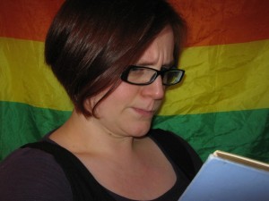 Hannah reading in front of a rainbow flag. Photo: the author.